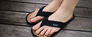 Pieds chaussés de tongs noires REuse me à semelle en liège – sandales de bain réutilisables et durables au Sunstar Hotel.