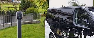 Borne de recharge électrique à côté du bus électrique de la Chäs Stuba au Sunstar Hotel Klosters – une mobilité durable au quotidien.