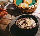Risotto finement présenté dans un bol noir, servi avec du pain et un verre de vin blanc – une cuisine régionale et durable au Sunstar Hotel.